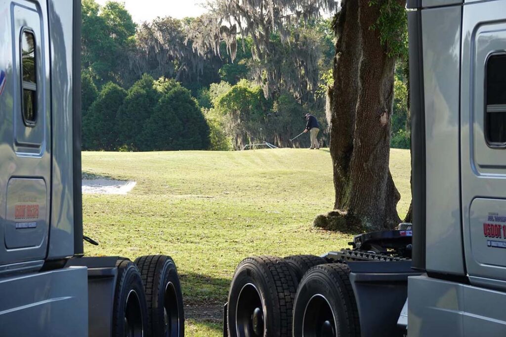 Trucks framing a distant golfer on course.