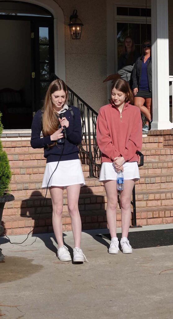 Two women speaking outdoors in casual attire.