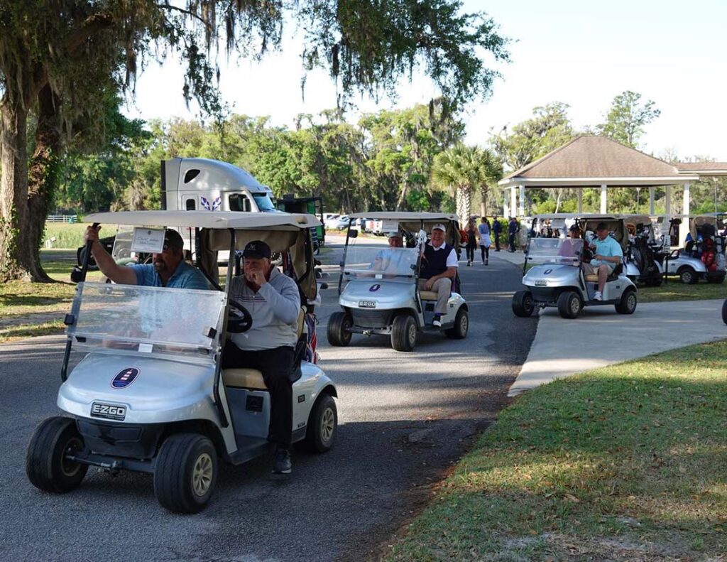 Players riding carts under mossy oak trees
