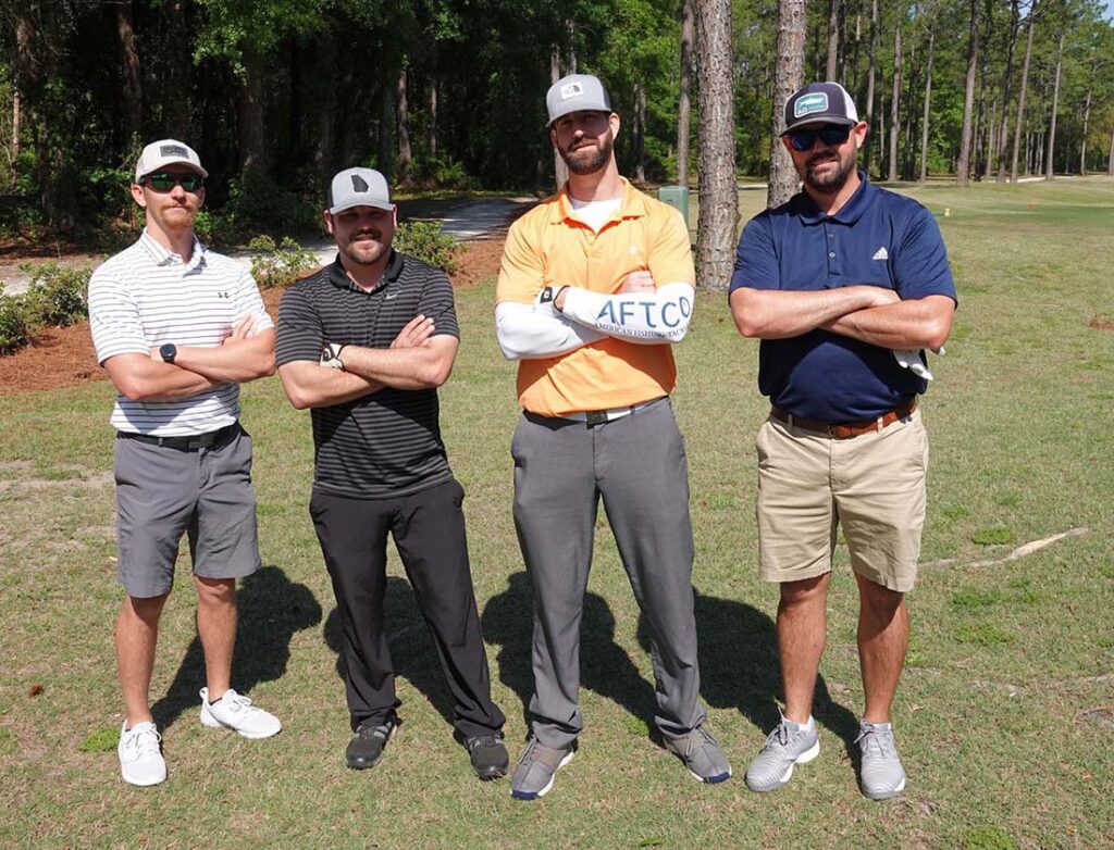 Foursome crossing arms on sunlit fairway