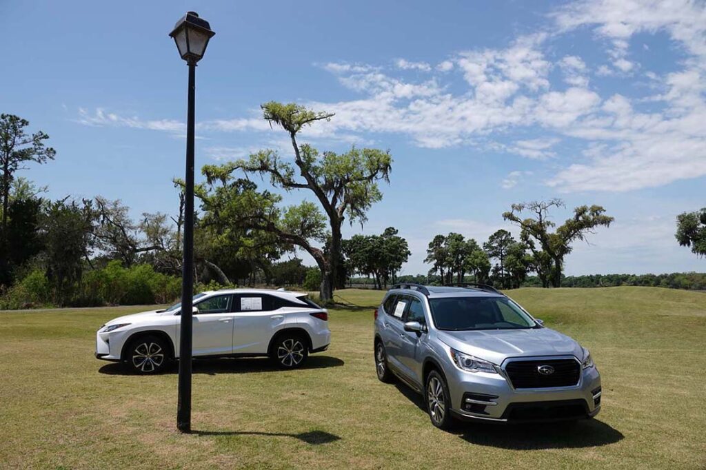 Two cars parked on grassy field.