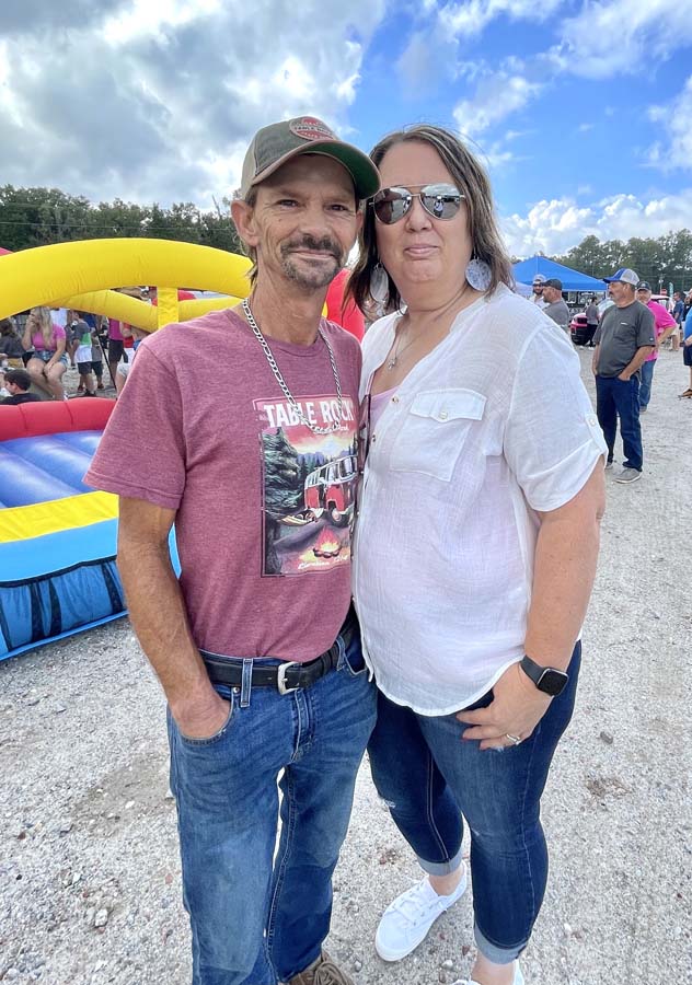 Couple posing outdoors at a festival.