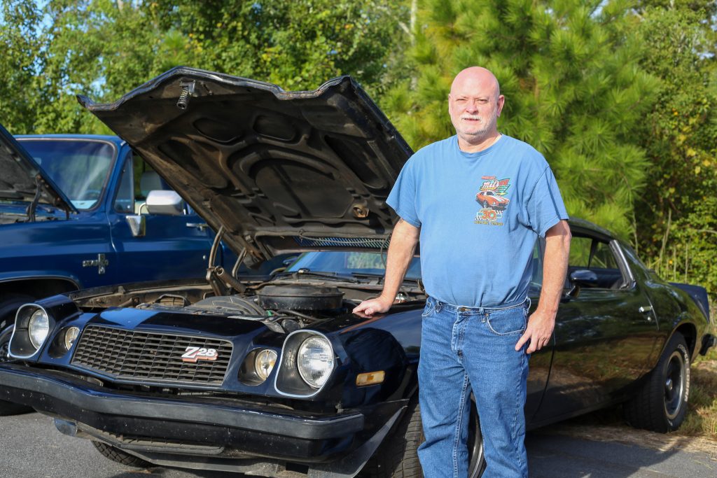 Man standing beside classic black car.