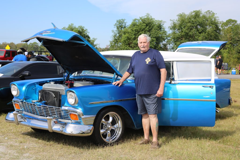 Older man beside open-hood turquoise classic Chevrolet