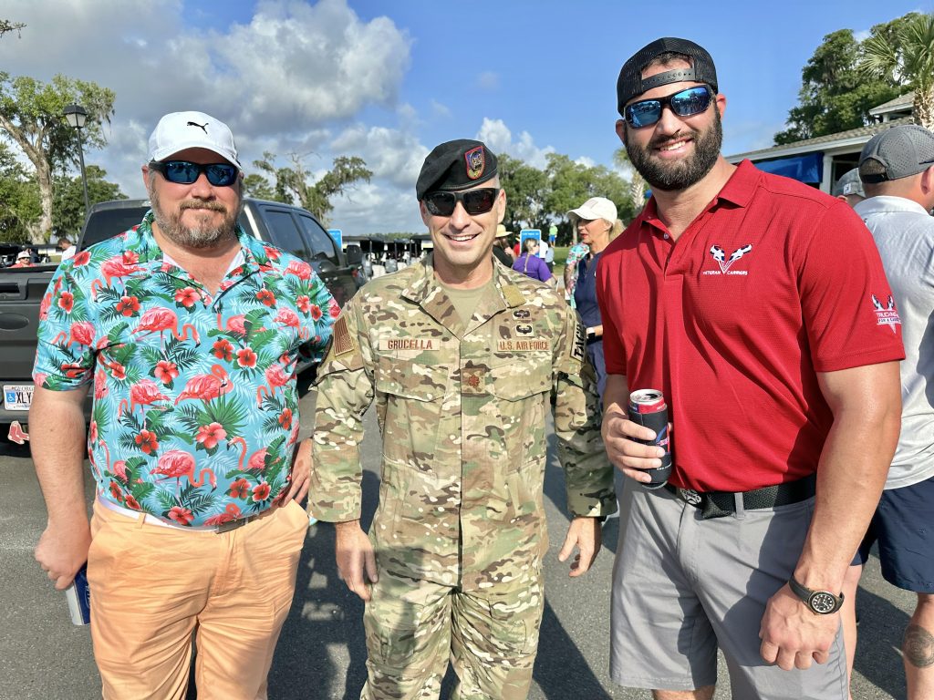 Three men posing outdoors, one in uniform.