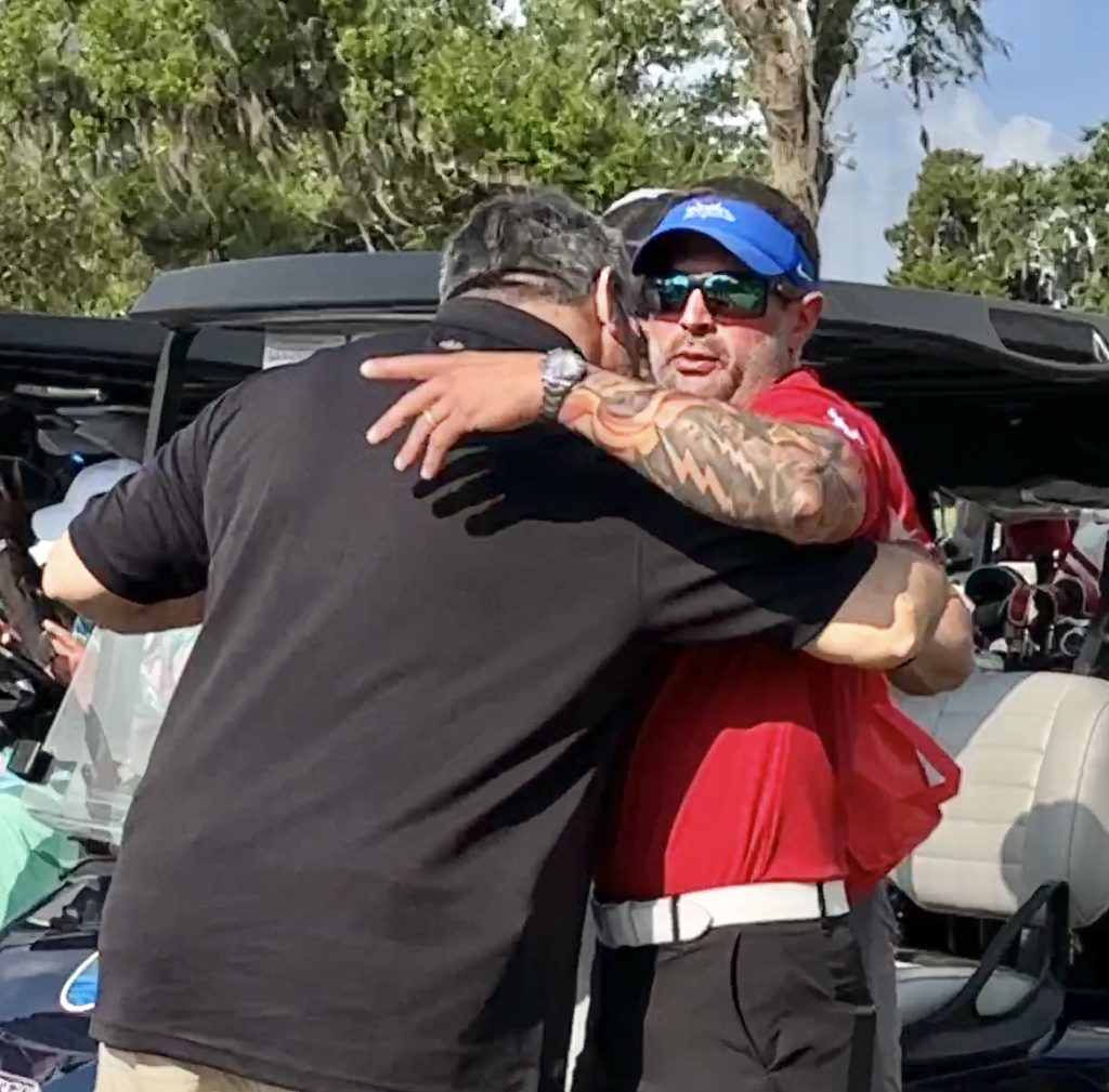 Two men embracing at a golf course.