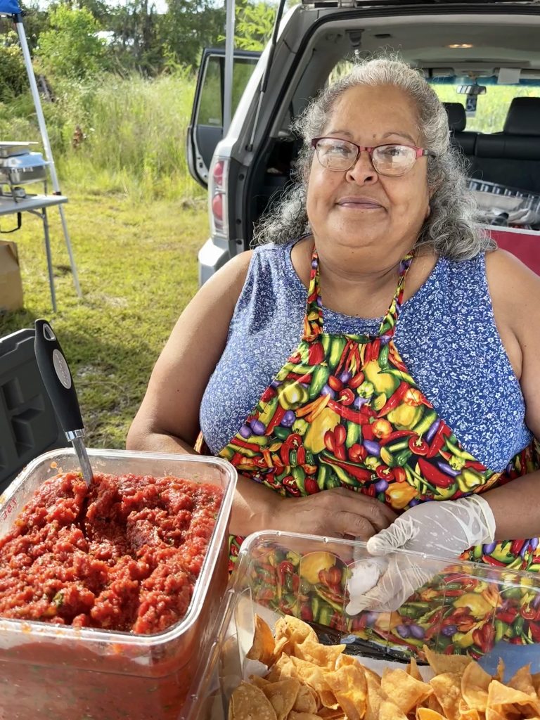 Woman selling salsa and chips outdoors.